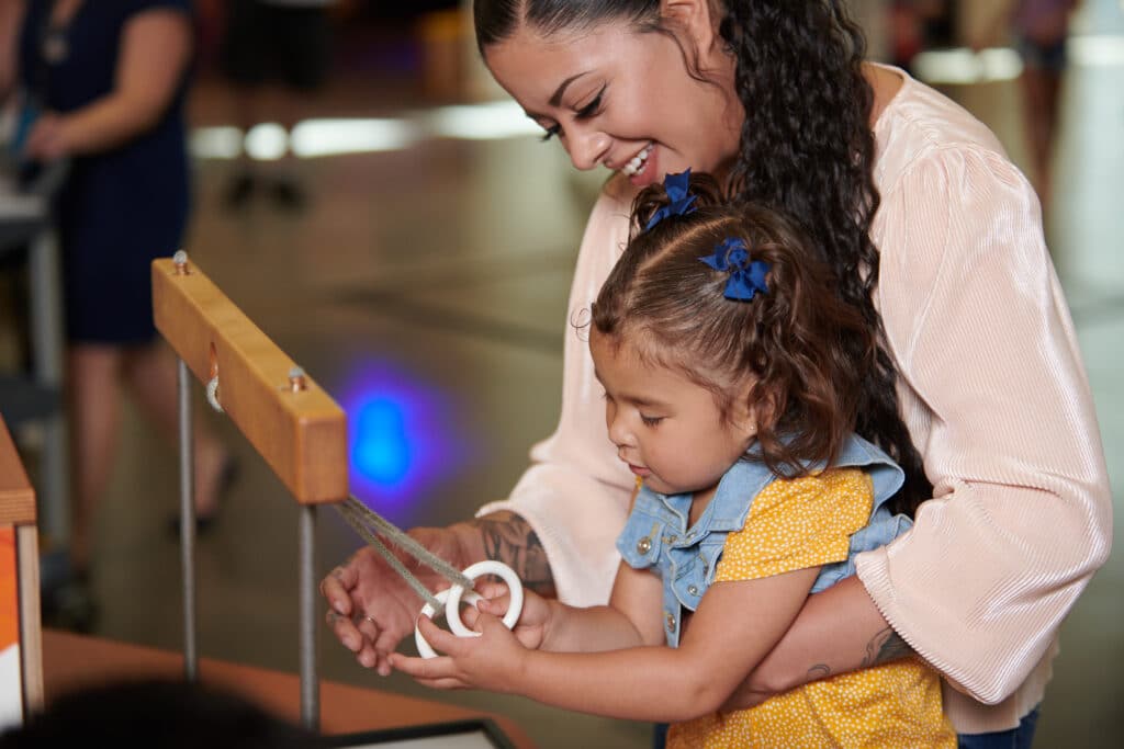 Photograph of a woman and child working on a rope puzzle.